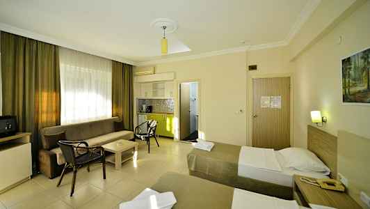 Hotellihuone, jossa on kaksi yhden hengen vuodetta, sohva, sohvapöytä ja pieni keittiö. (Tekoälyn luoma teksti)