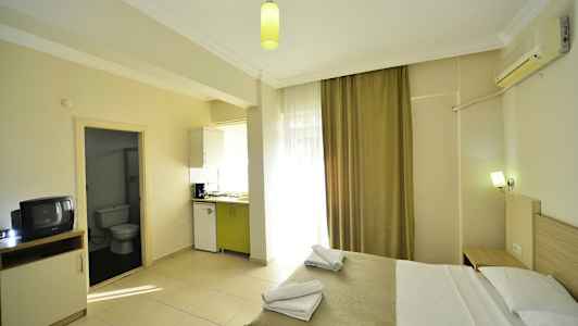 Hotellihuone, jossa sänky, keittiöosa ja kylpyhuoneen sisäänkäynti. (Tekoälyn luoma teksti)