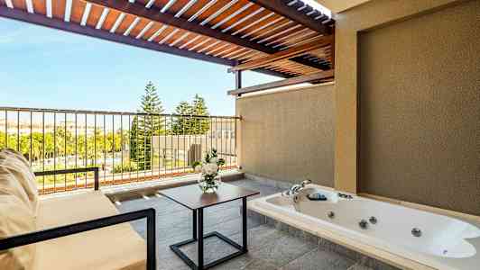 Terassi, jossa poreallas, istuinkalusteet, kukka-asetelma ja näkymä vehreään maisemaan. (Tekoälyn luoma teksti)