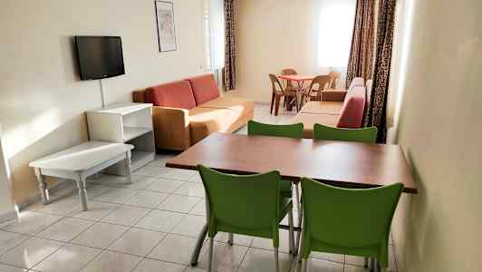 Olohuone, jossa on sohvia, ruokapöytä tuoleineen ja seinälle kiinnitetty televisio. (Tekoälyn luoma teksti)