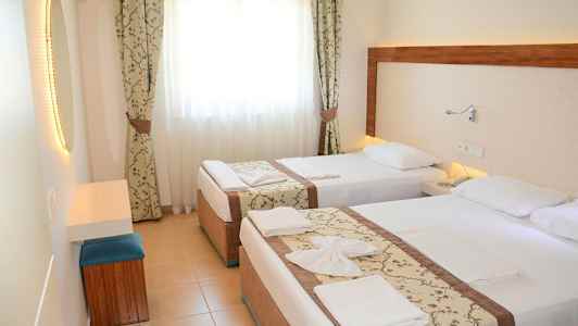 Hotellihuone, jossa kaksi erillistä sänkyä, vaaleat verhot ja peili. (Tekoälyn luoma teksti)