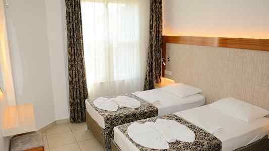 Hotellihuone, jossa on kaksi erillistä vuodetta ja koristeelliset vuodevaatteet. (Tekoälyn luoma teksti)