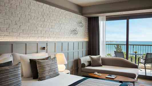 Kuva modernista hotellihuoneesta, jossa on merinäköala parvekkeelta. (Tekoälyn luoma teksti)