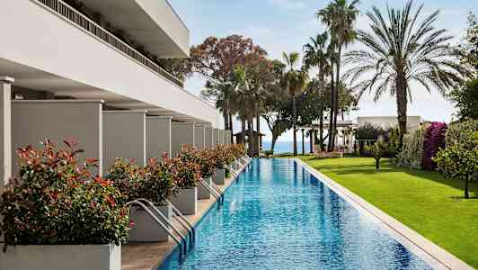 Pitkä uima-allas, jota ympäröi vehreys ja modernit rakennukset. (Tekoälyn luoma teksti)