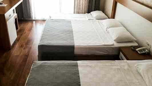 Hotellihuone, jossa kaksi sänkyä ja kirjoituspöytä. (Tekoälyn luoma teksti)