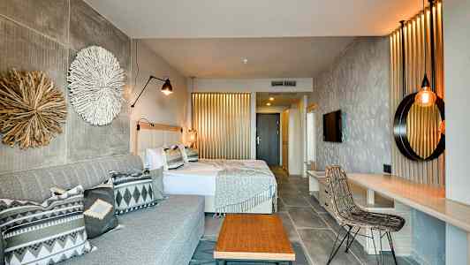 Hotellihuone, jossa kaksi sänkyä, sohva ja sisustuselementtejä. (Tekoälyn luoma teksti)