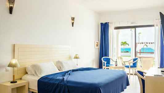 Hotellihuone, jossa sänky, huonekaluja ja merinäköala. (Tekoälyn luoma teksti)