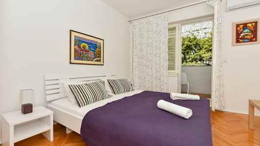 Makuuhuone, jossa on parivuode, violetti päiväpeite ja kaksi taiteltua pyyhettä. (Tekoälyn luoma teksti)