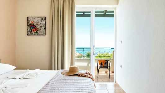 Hotellihuone, jossa on sänky, hattu ja ikkuna, josta näkyy meri. (Tekoälyn luoma teksti)