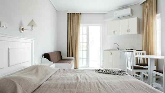 Hotellihuoneen yleiskuva, jossa on sänky, sohva, keittiö ja ruokapöytä. (Tekoälyn luoma teksti)