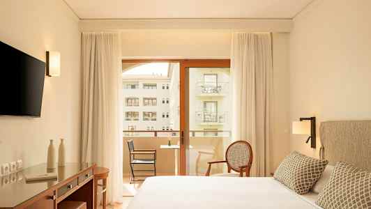 Moderni hotellihuone, jossa parivuode, kirjoituspöytä, televisio ja parveke näkymällä. (Tekoälyn luoma teksti)