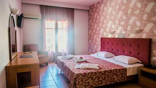 Hotellihuone, jossa on parivuode, työpöytä, nojatuoli ja koristeltu seinä. (Tekoälyn luoma teksti)