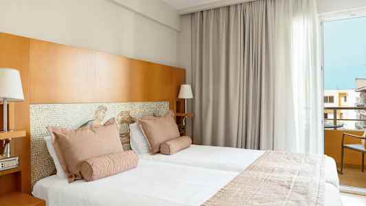 Kaksi vuodetta hotellihuoneessa, jossa vaaleat tekstiilit ja puuyksityiskohtia. (Tekoälyn luoma teksti)