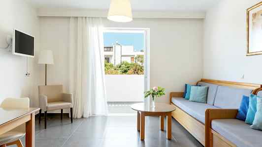 Valoisa olohuone, jossa on sohva, pöytä ja tuolit sekä avautuminen parvekkeelle. (Tekoälyn luoma teksti)