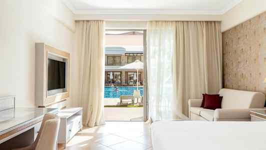 Hotellihuone, jossa parveke, sänky, sohva ja näkymä uima-altaalle. (Tekoälyn luoma teksti)