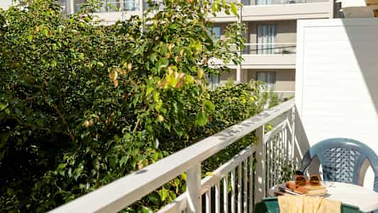 Kuva parvekkeesta, jossa pöytä, tuoli ja vihreää kasvillisuutta etualalla. (Tekoälyn luoma teksti)