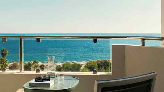 Näköala merelle parvekkeelta, pöydällä lasi ja kirja. (Tekoälyn luoma teksti)