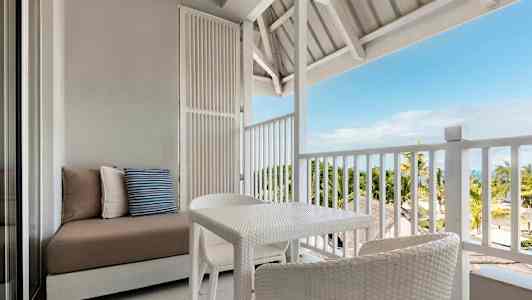 Huonekalut avoimella parvekkeella näkymällä palmuihin ja mereen. (Tekoälyn luoma teksti)