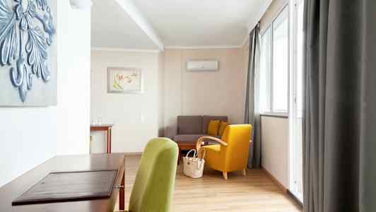 Hyvin kalustettu olohuone, jossa on vihreä ja keltainen tuoli, sohva ja työpöytä. (Tekoälyn luoma teksti)