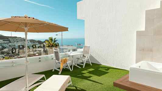 Terassi, jossa aurinkotuoleja, varjo ja pöytä tuoleineen, taustalla merinäköala. (Tekoälyn luoma teksti)