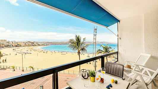 Näkymä parvekkeelta hiekkarannalle ja merelle, etualalla pöytä ja tuolit. (Tekoälyn luoma teksti)