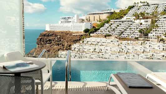 Näkymä terassilta, jossa uima-allas, kohti vuorta ja rakennuksia. (Tekoälyn luoma teksti)