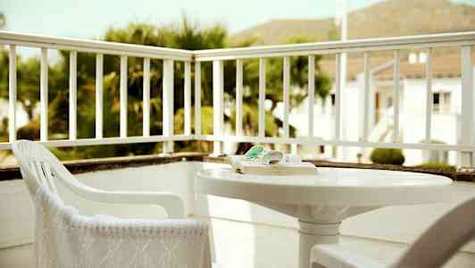 Puutarhatasanne, jossa tuoleja ja pöytä, ympärillä kaiteet. (Tekoälyn luoma teksti)