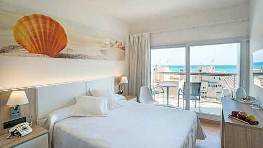 Hotellihuone, jossa on parivuode, koristeellinen taideteos oranssista simpukasta seinällä ja parveke merinäköalalla. (Tekoälyn luoma teksti)