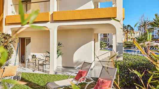 Ulkoalue, jolla on nurmikko, aurinkotuoleja ja varjo hotellin yhteydessä. (Tekoälyn luoma teksti)