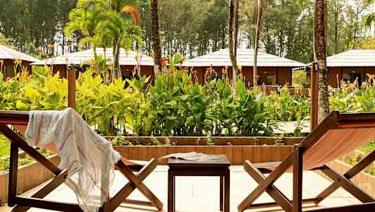 Kaksi aurinkotuolia ja pieni pöytä niiden välissä, ulkoterassilla trooppisen puutarhan näkymällä. (Tekoälyn luoma teksti)