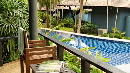 Näkymä verannalta uima-altaalle, jota ympäröivät vihreät kasvit ja puut. (Tekoälyn luoma teksti)