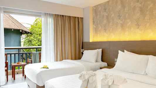 Kaksi pedattua yhden hengen sänkyä koristeellisilla pyyhkeillä ja kukilla. Näkymä kalustetulle parvekkeelle, jossa vihreää ja rakennus. (Tekoälyn luoma teksti)