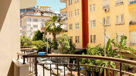 Näkymä parvekkeelta kadulle, jota ympäröivät rakennukset ja vehreys. (Tekoälyn luoma teksti)