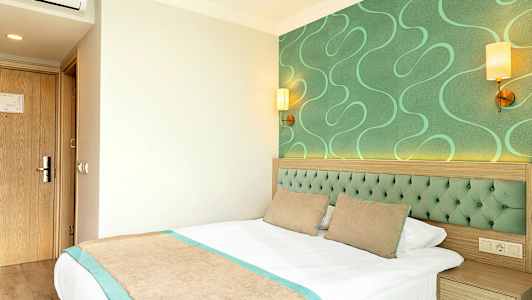 Hotellihuone vihreillä yksityiskohdilla ja sänky. (Tekoälyn luoma teksti)