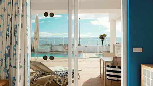 Kuva aurinkotuolista ja uima-altaasta, katsottuna terassilta lasiovien läpi. (Tekoälyn luoma teksti)