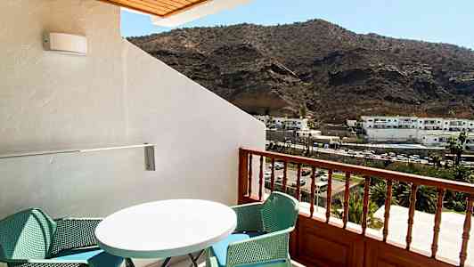 Parveke, jossa huonekaluja ja näkymä vuorille. (Tekoälyn luoma teksti)