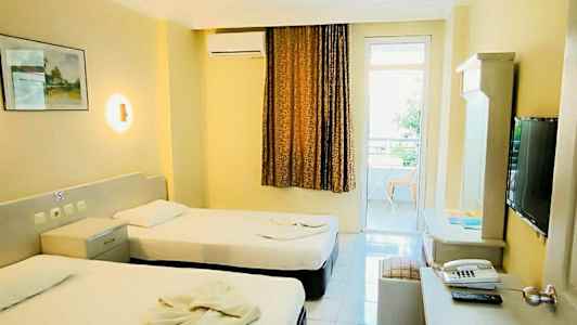 Hotellihuone, jossa kaksi yhden hengen vuodetta, kirjoituspöytä ja televisio. (Tekoälyn luoma teksti)