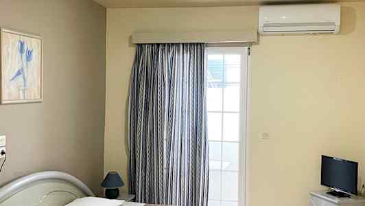 Hotellihuone, jossa kaksi yhden hengen vuodetta, televisio ja ikkuna verhoilla. (Tekoälyn luoma teksti)