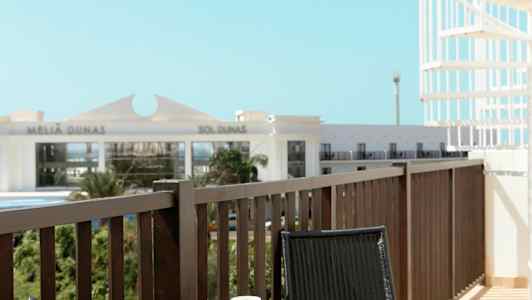 Parveke, jossa pöytä ja kaksi tuolia. Pöydällä on kahvikuppi ja avattu kirja. (Tekoälyn luoma teksti)