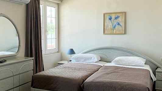 Hotellihuone, jossa on kaksi yhden hengen vuodetta, työpöytä ja peili. (Tekoälyn luoma teksti)