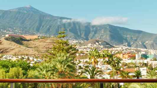 Parveke, jolla on pöytä, johon on tarjoiltu ruokaa ja juomia; näkymä kaupunkiin, taustalla vuoria. (Tekoälyn luoma teksti)