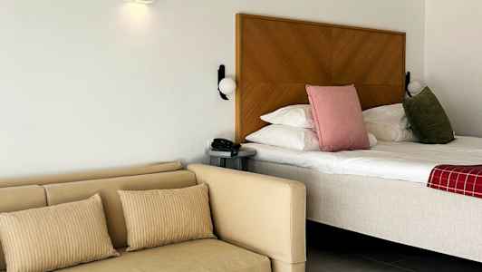 Hotellihuone, jossa on sänky, sohva ja pöytä. (Tekoälyn luoma teksti)