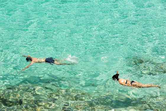 Kaksi henkilöä snorklaa kirkkaassa turkoosissa vedessä. (Tekoälyn luoma teksti)