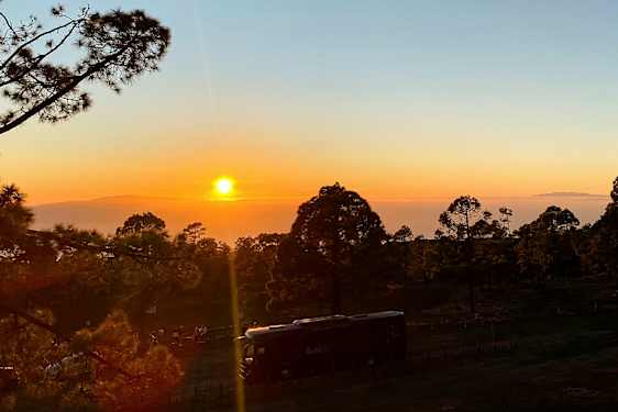 Kuva auringonlaskusta metsän yllä, etualalla yksi ajoneuvo. (Tekoälyn luoma teksti)