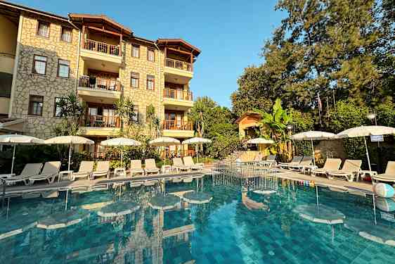 Hotellin julkisivu, edessä uima-allas ja aurinkotuoleja. (Tekoälyn luoma teksti)