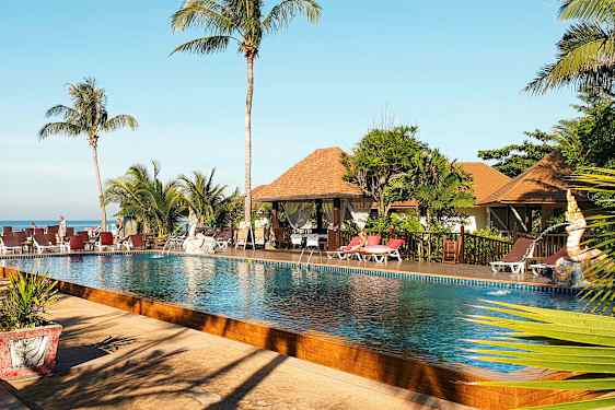 Kuva uima-allasalueesta, jossa on palmuja, aurinkotuoleja ja bungalow-tyylisiä rakennuksia taustalla. (Tekoälyn luoma teksti)