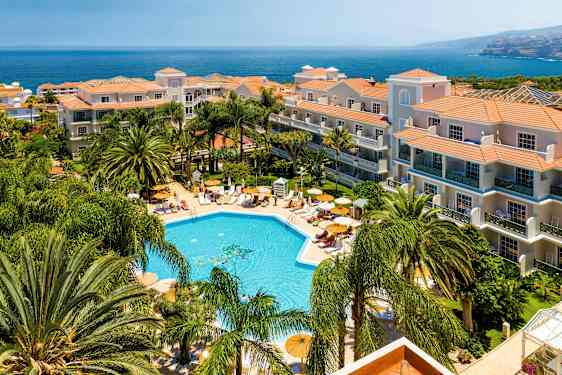 Hotelli, jossa on uima-allasalue ja ympäröivää vehreyttä rannikon läheisyydessä. (Tekoälyn luoma teksti)