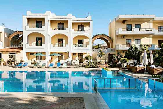 Hotellikompleksi, jossa on parvekkeita ja uima-allas rakennuksen edessä. Uima-altaan ympärillä on aurinkotuoleja ja aurinkovarjoja. (Tekoälyn luoma teksti)