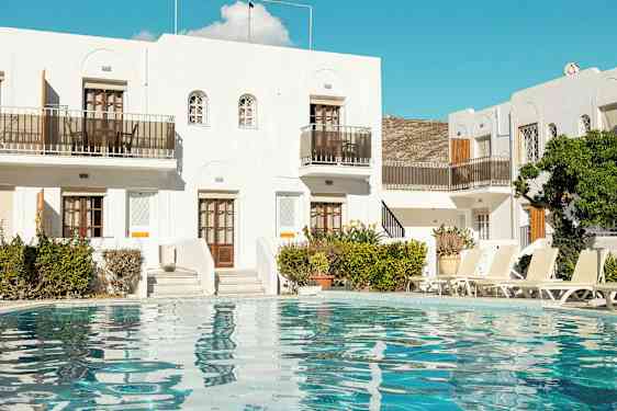 Valkoinen rakennus, jonka edessä on uima-allas ja aurinkotuoleja. (Tekoälyn luoma teksti)