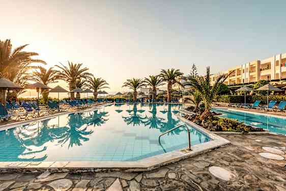 Ulkoallas, jossa aurinkotuoleja ja aurinkovarjoja auringonlaskun aikaan. (Tekoälyn luoma teksti)